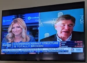 a picture of a television showing a news interview with the headline, cooperman: market structure is totally broken