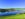 picture of a lake with green landscape in the foreground and mountains in the background