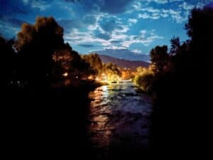 an image of a river at night with glowing lights in the distance along the bank