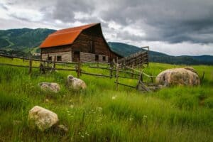image of a farmhouse and greenery below an ominous sky